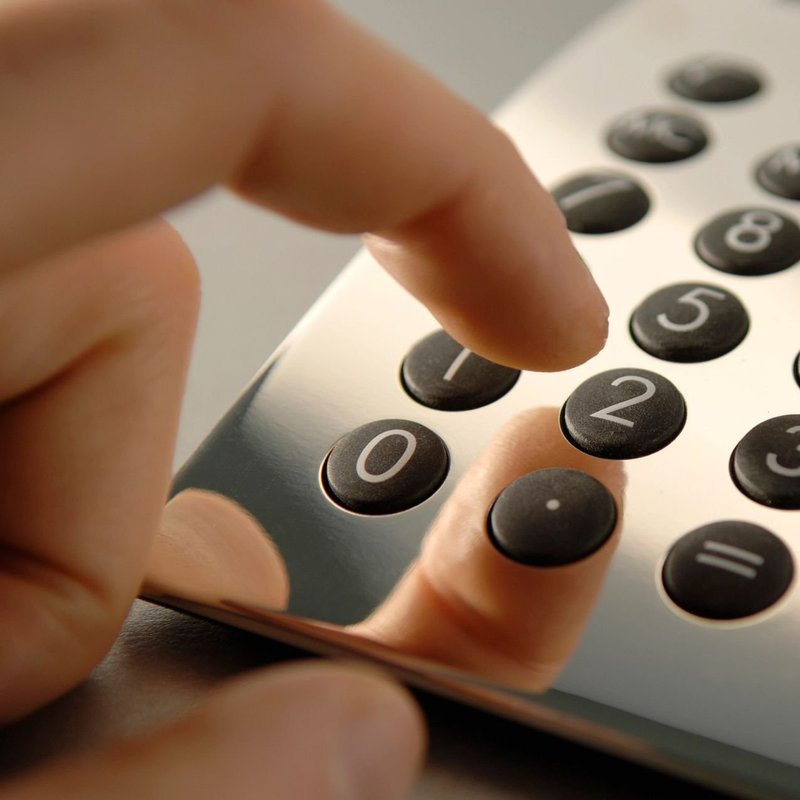 closeup of a hand using an analogue calculator from Carpet Plus Inc