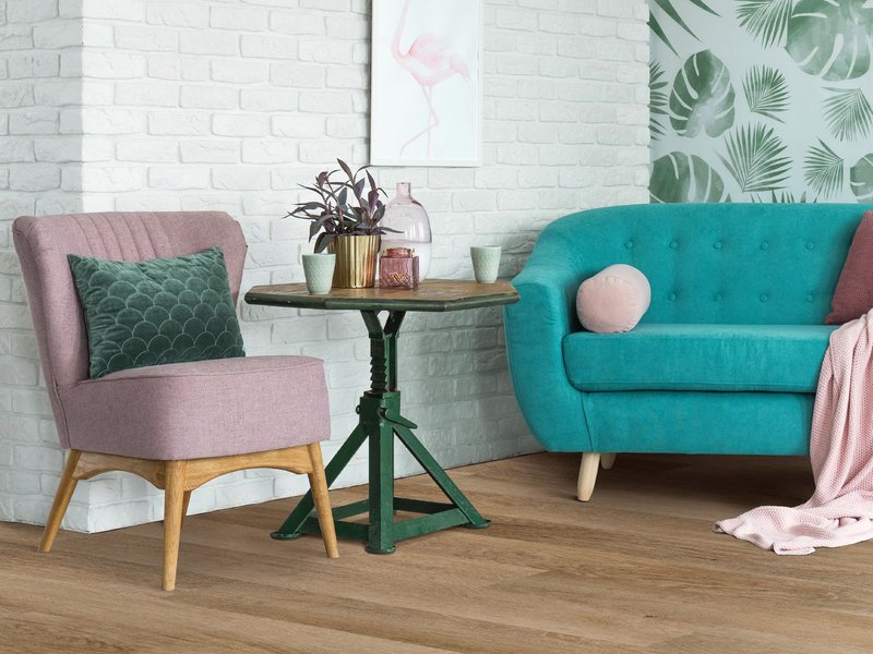 pink arm chair and teal couch on wood look flooring - Carpet Plus Flooring LLC