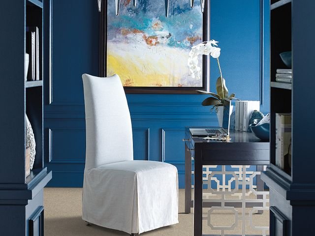 white covered chair in room with blue walls and colorful painting - Carpet Plus Flooring LLC