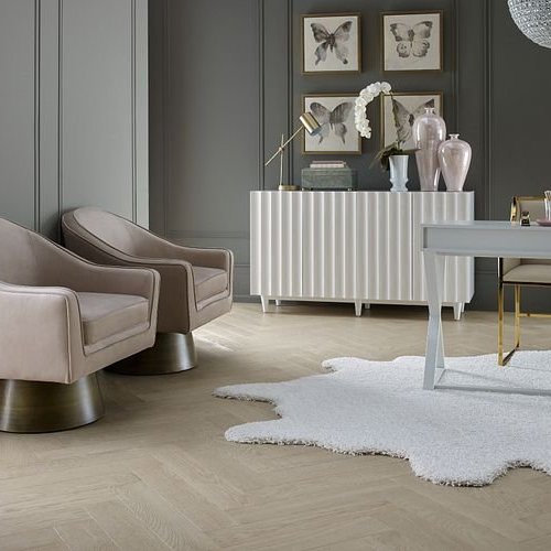 pair of luxurious arm chairs with irregular area rug on herringbone floors from Carpet Plus Inc